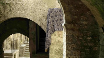 An arched stone corridor with a patterned cloth hanging on the wall.