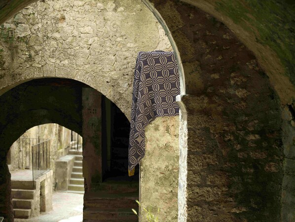 An arched stone corridor with a patterned cloth hanging on the wall.