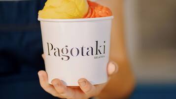 A person holding a cup of gelato with the brand name 'Pagotaki' visible on it.