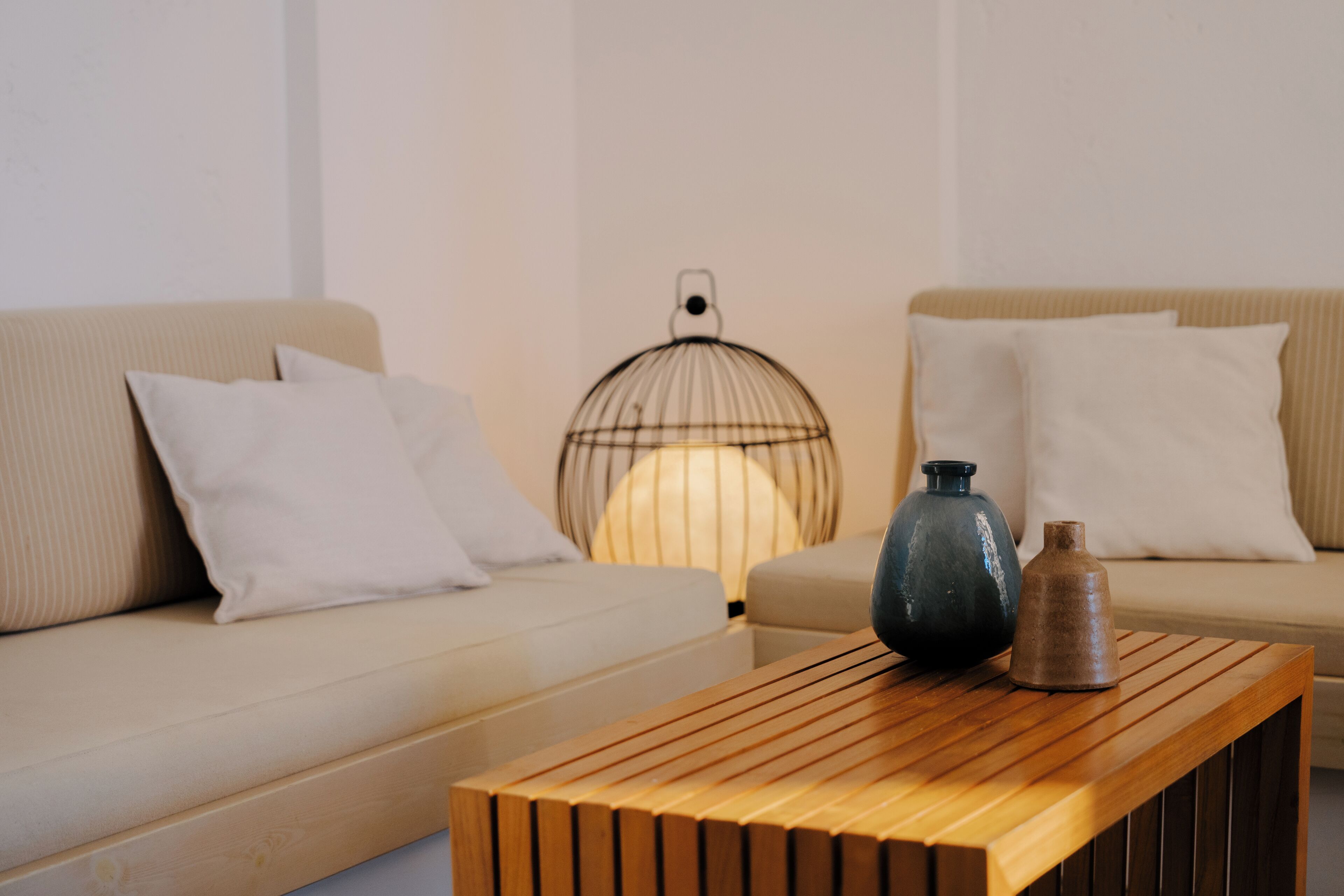 Een moderne woonkamer met een houten salontafel, twee banken en een decoratieve lamp.
