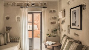 Ein gemütliches Zimmer mit Steinwand, einer Couch, einem kleinen Tisch und einem gerahmten Bild.