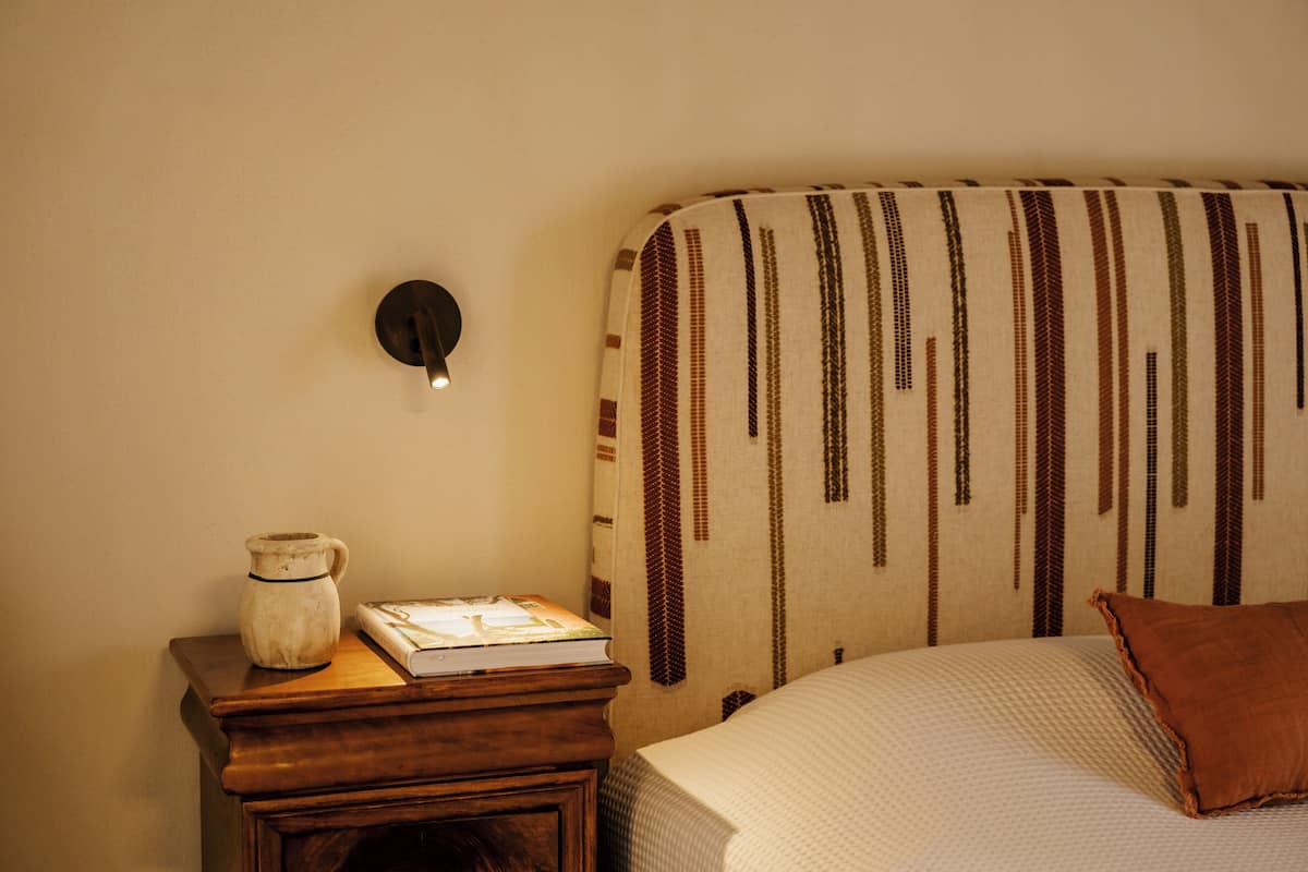 Une chambre à coucher avec un lit, une table de chevet, une lampe et un livre.