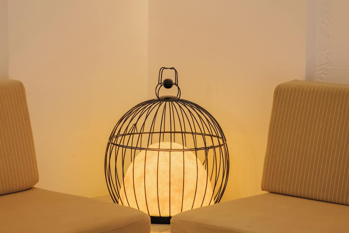 Une pièce comprenant un canapé, une table avec un saladier de fruits et un luminaire décoratif.