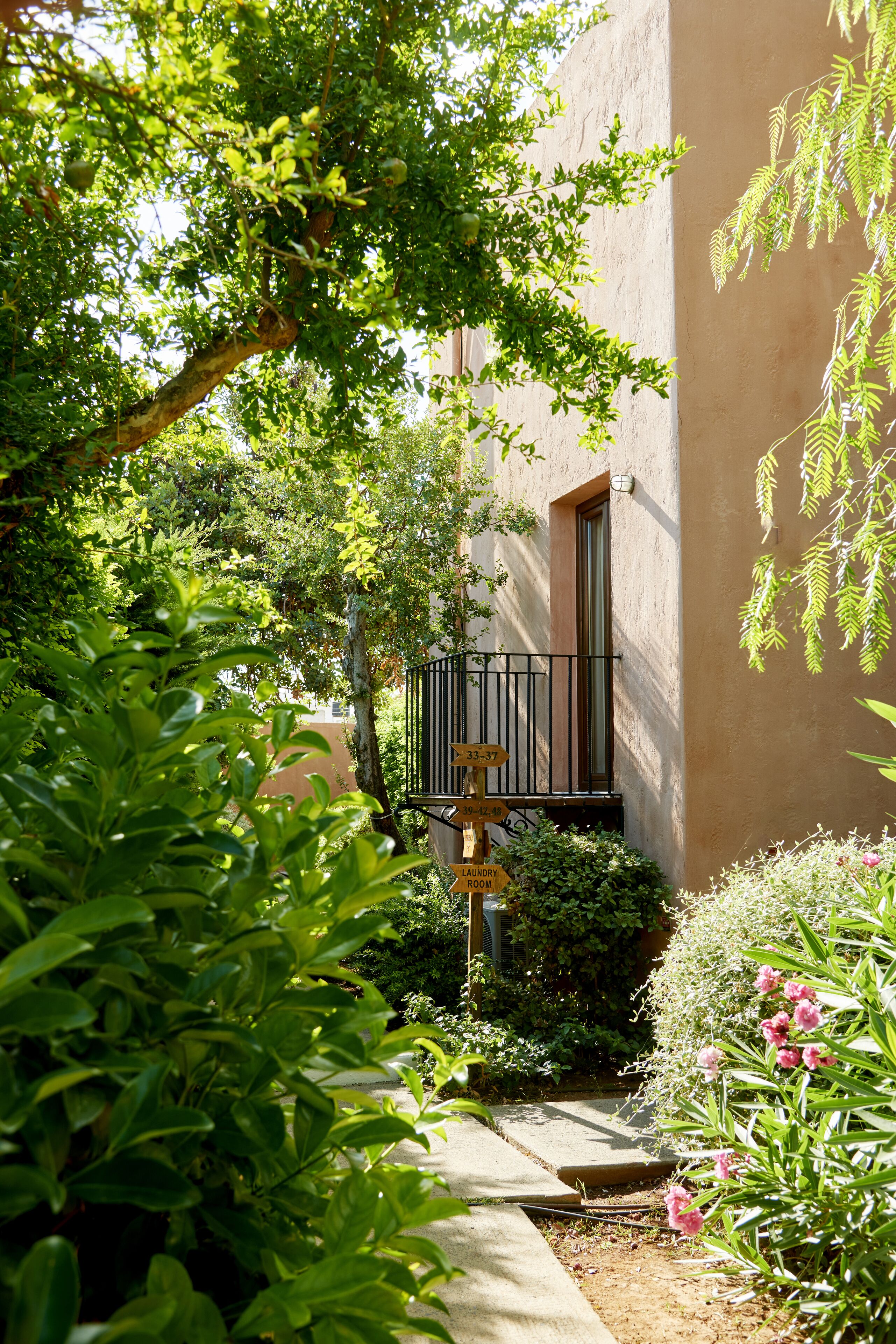 A courtyard with a laundry room sign, a metal gate, and lush greenery.
