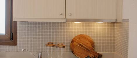 Eine Küche mit Spüle aus Edelstahl, Schneidebrett aus Holz und Glasbehältern.