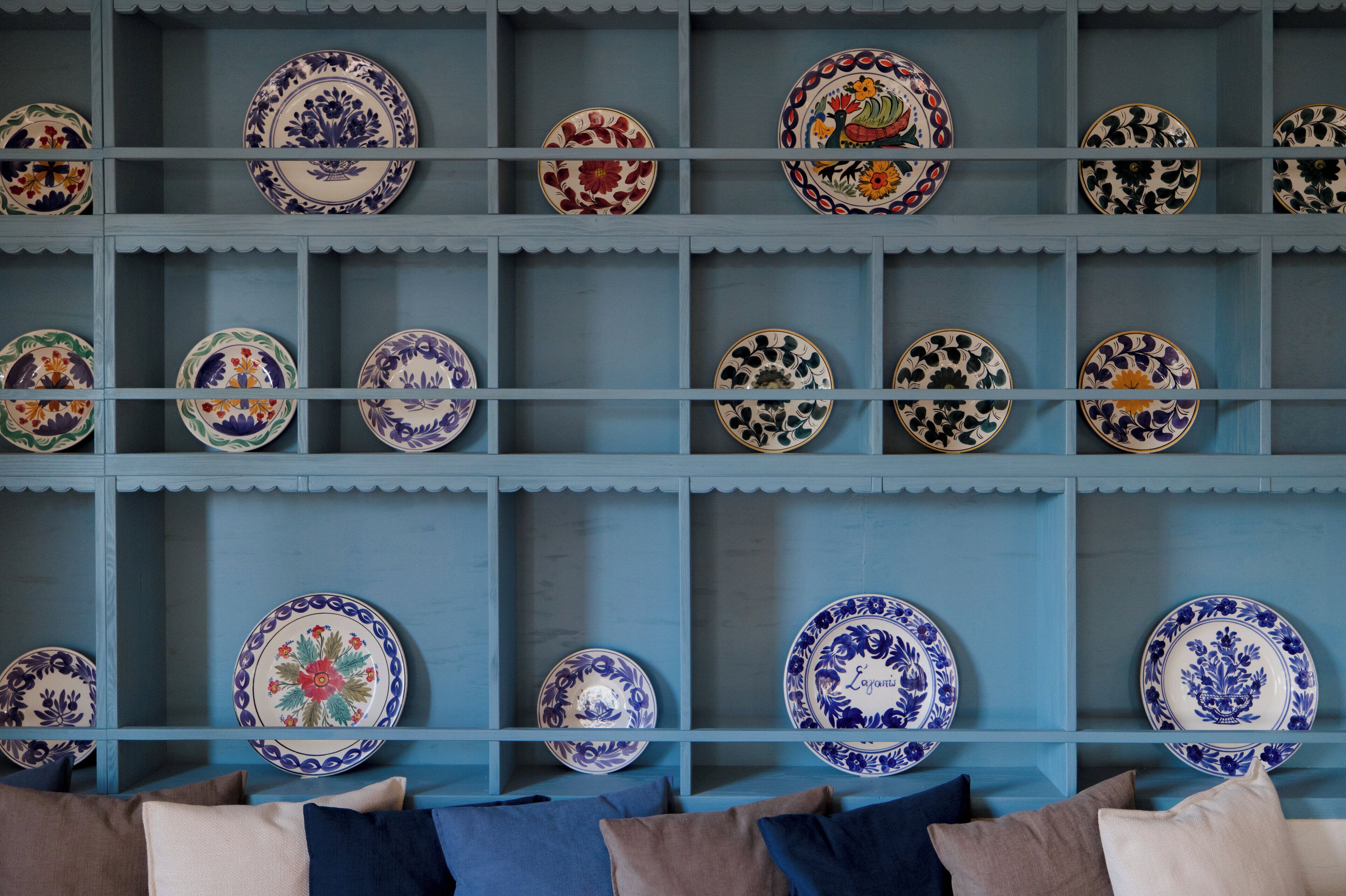 A blue shelving unit displaying various ceramic plates with floral designs.