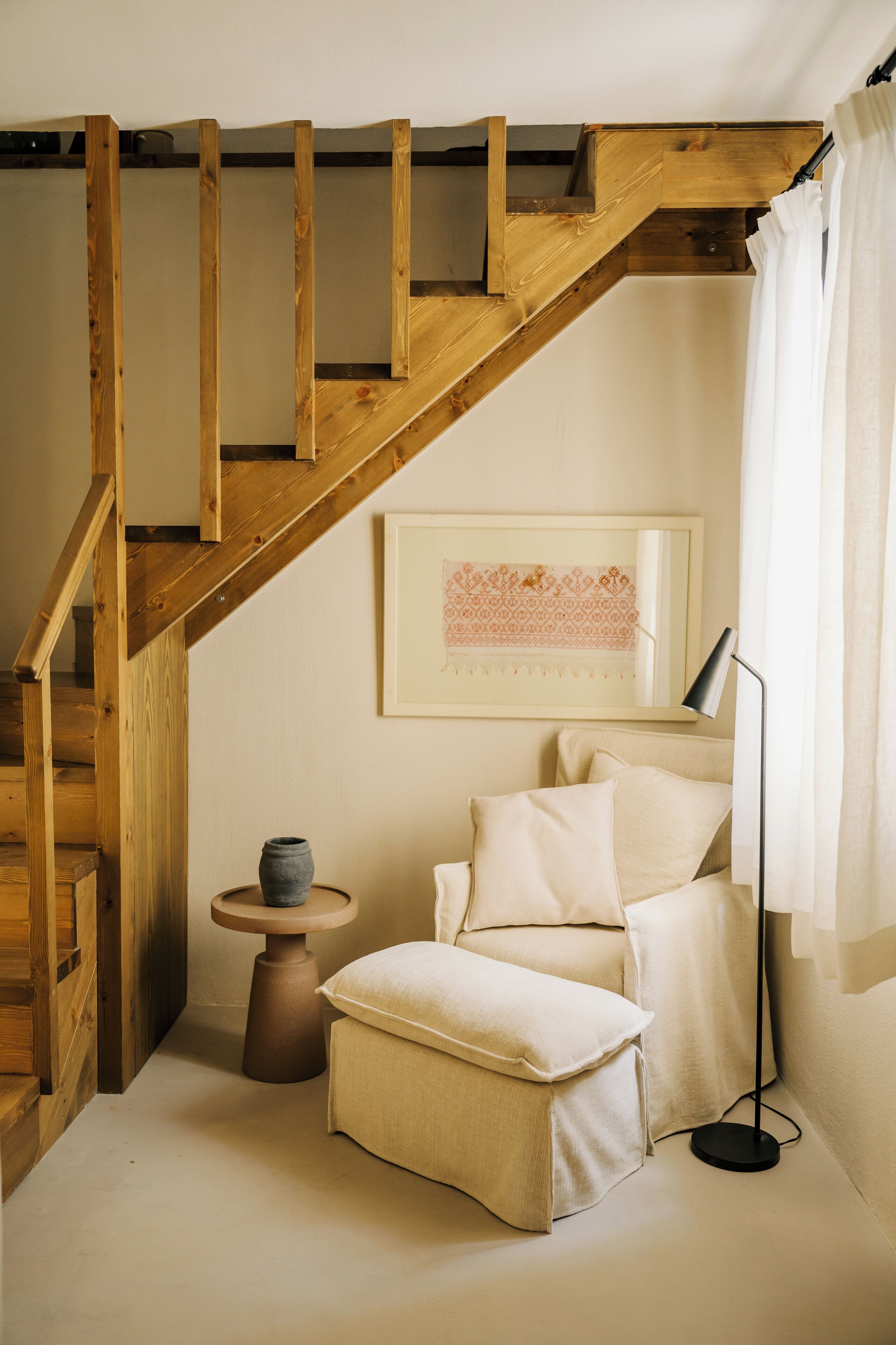 Un escalier en bois mène à une chambre à coucher qui contient un lit, une table de chevet et une lampe.