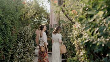 Dos mujeres caminando por un sendero rodeado de abundante vegetación y árboles.