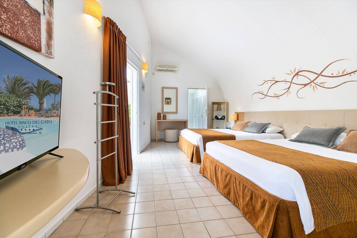 A hotel room with two beds, a TV, a desk, and a bathroom.