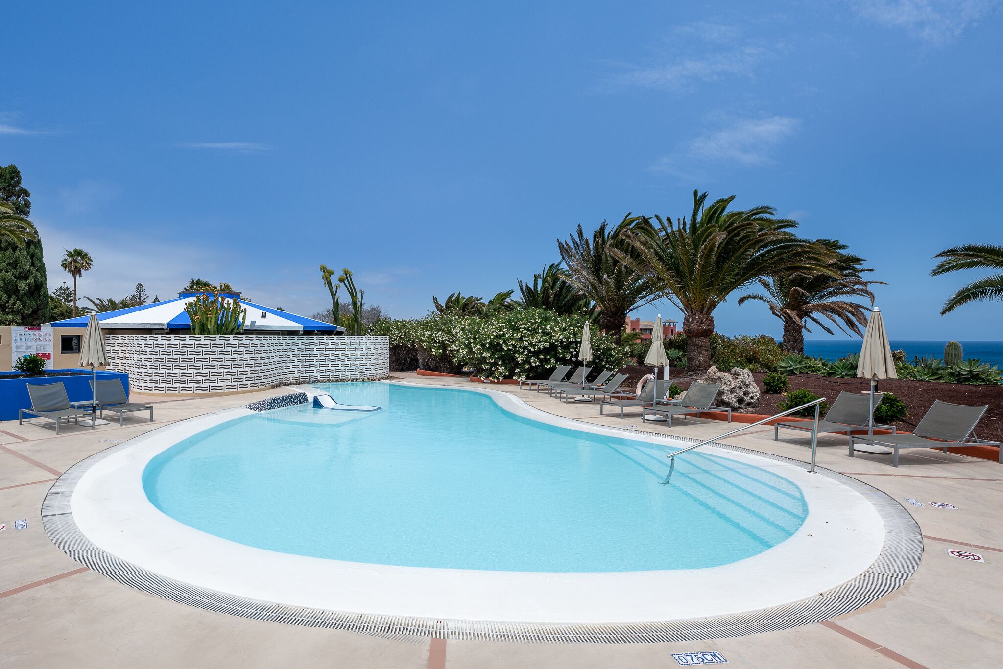 A swimming pool with lounge chairs and a view of the ocean.
