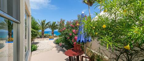 A patio with a table and chairs, surrounded by plants and a view of the ocean.