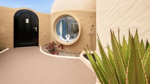 Un bâtiment moderne doté d’une fenêtre circulaire, d’une porte noire et d’une façade de couleur beige.
