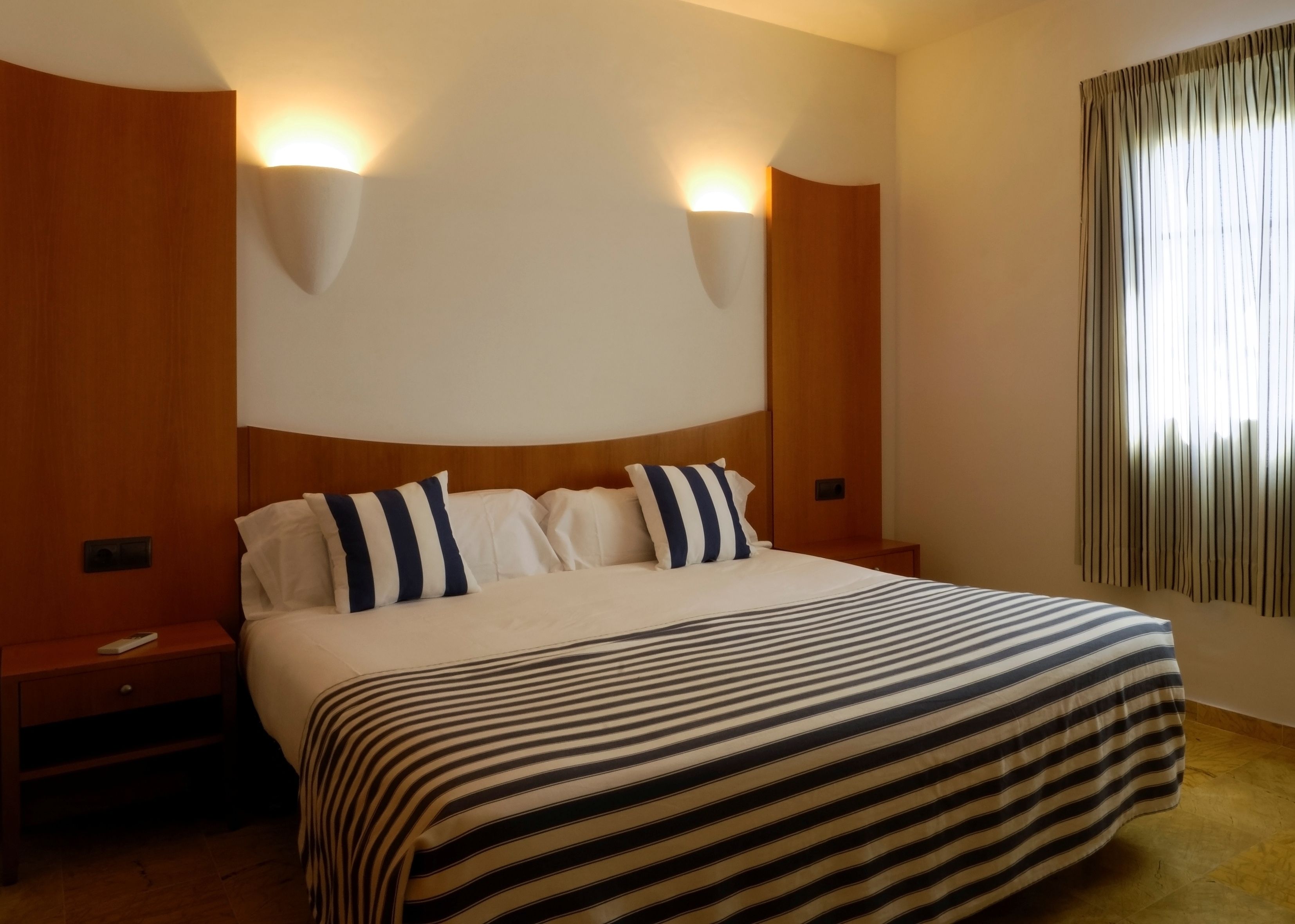 Ein Hotelzimmer mit einem großen Bett, zwei Nachttischen und zwei Wandleuchten.