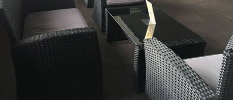 A modern indoor seating area with wicker furniture and potted plants.