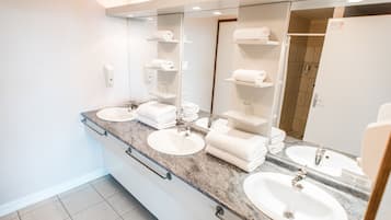 A modern bathroom with two sinks, a large mirror, and towel racks.