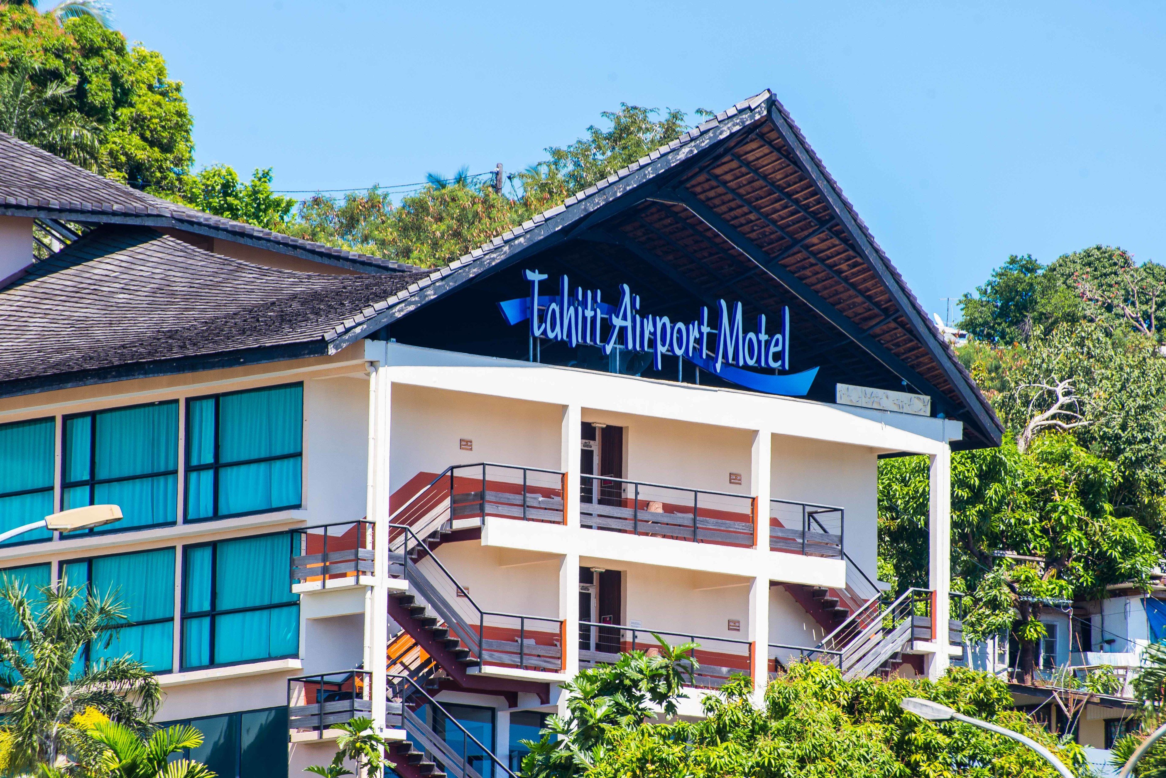 Un edificio con un letrero que dice "Tahiti Airport Motel". Tiene varios pisos con balcones y una escalera.