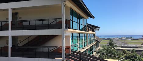 A multi-story building with a red and white facade, large windows, and a view of the ocean.