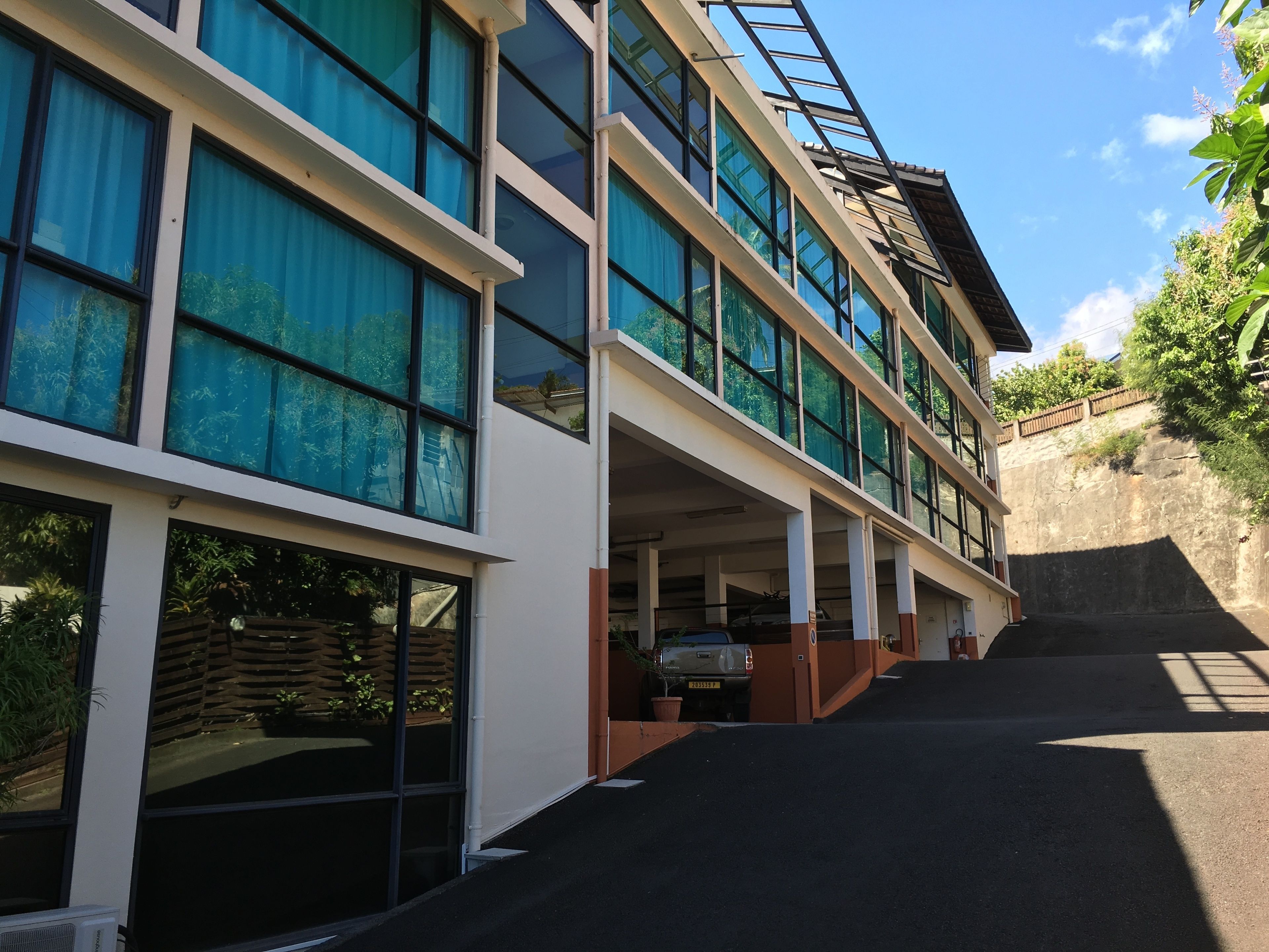 Un bâtiment moderne à plusieurs étages, doté de grandes fenêtres et d’un espace de stationnement couvert.