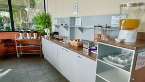 A modern kitchen with white cabinets, a countertop with various appliances, and a glass display case. - Tahiti Airport Motel (Faaa)
