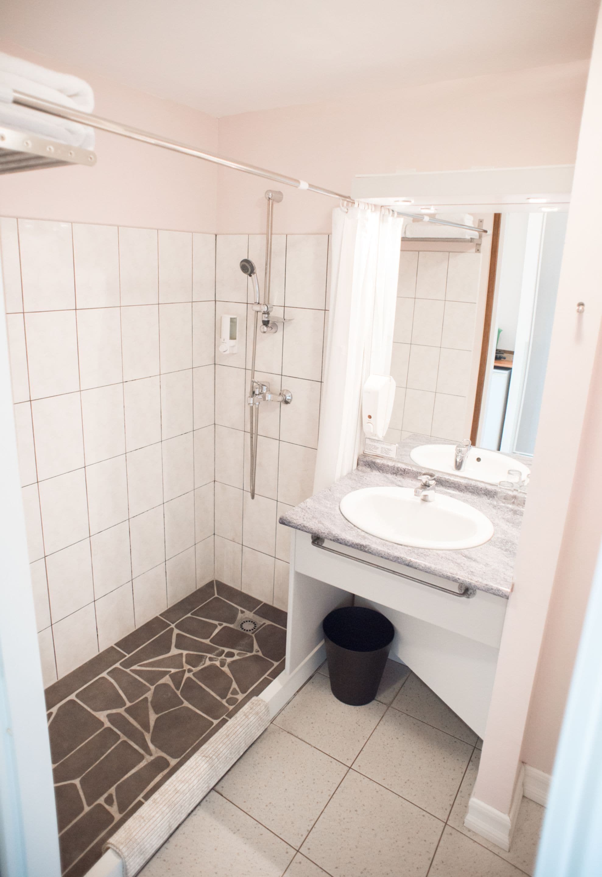 A bathroom with a shower, a sink, and a mirror.
