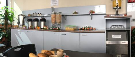 A breakfast setup with a tray of croissants, coffee cups, and flowers on a table.