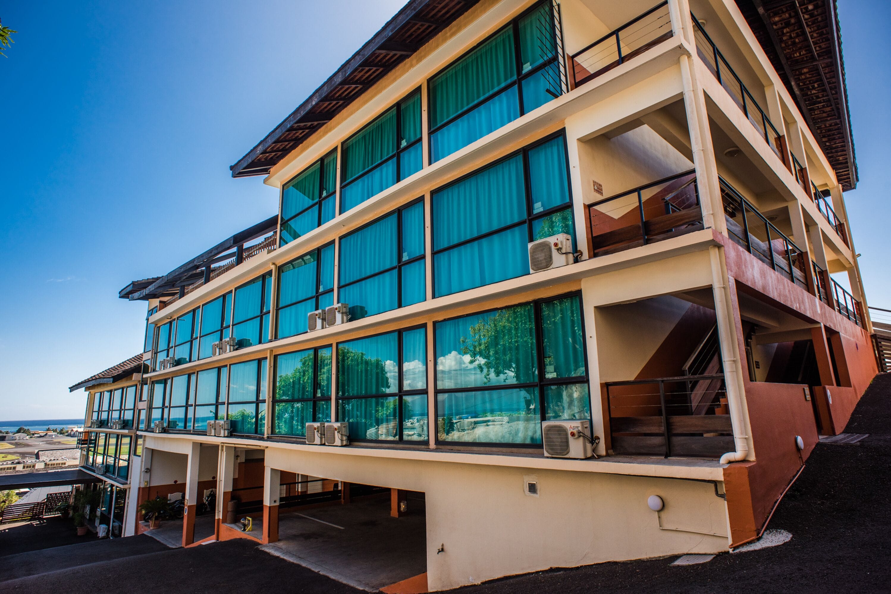 A multi-story hotel with large windows, balconies, and a view of the ocean.