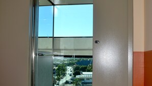 A modern hotel room with a sliding glass door leading to a balcony with a city view. - Tahiti Airport Motel (Faaa)