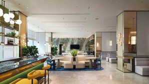 A modern hotel lobby with a bar area, seating arrangements, and a television screen. - Nina Hotel Island South (Hong Kong)