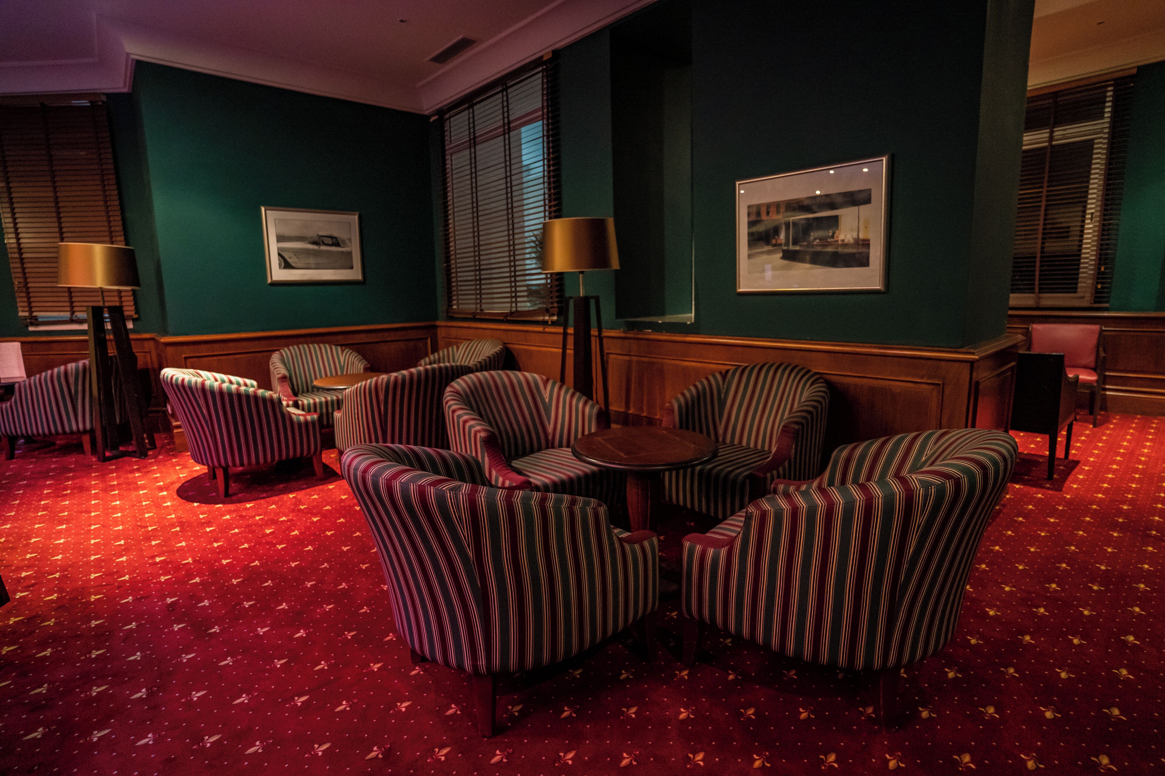 A room with striped armchairs, a round table, and a red carpet.