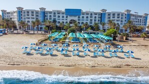 A beachfront hotel with multiple levels, a pool area with umbrellas, and a sandy beach. - Vincci Saphir Palace & Spa (Hammamet)