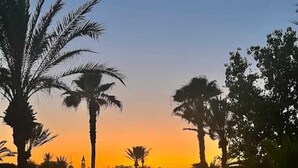 A paved pathway leading to a building with a dome, surrounded by palm trees and greenery. - Vincci Saphir Palace & Spa (Hammamet)