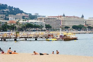 A coastal cityscape with a beach, a pier with boats, and a large building with the name 'Carlton' visible. - ibis budget Cannes centre ville (Cannes)