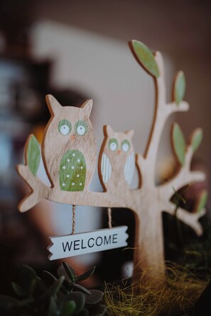 Un arbre en bois orné de deux figurines de hiboux et d’une pancarte indiquant « BIENVENUE ».