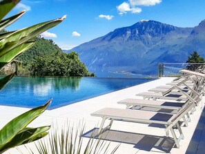 A pool area with lounge chairs, a mountain view, and a clear sky. - Stella D'Oro (Tremosine)