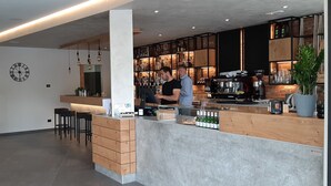 A modern bar area with a wooden counter, bar stools, and a variety of bottles and glasses. - Stella D'Oro (Tremosine)