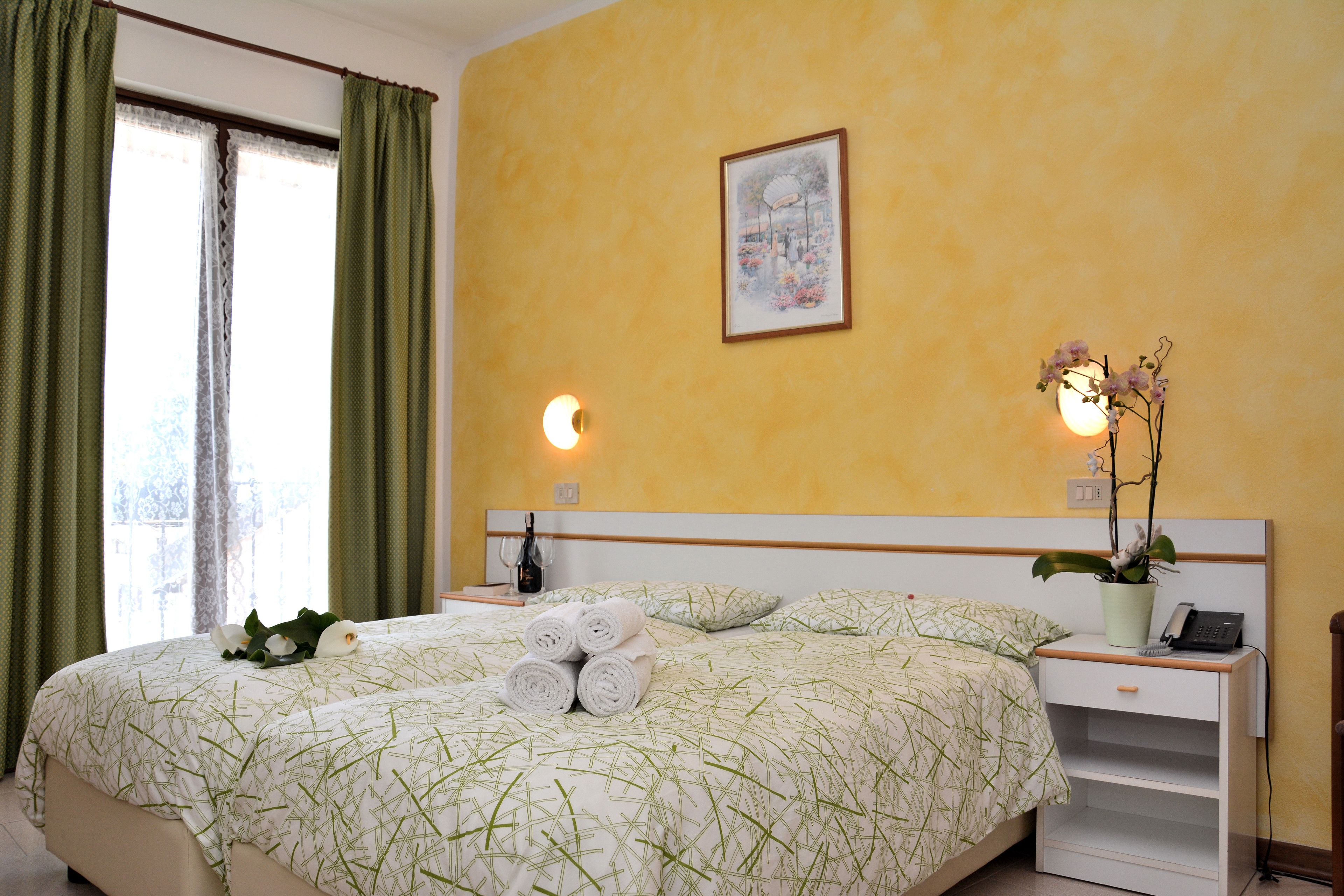Een hotelkamer met een bed, nachtkastje, een wandlamp en een potplant.