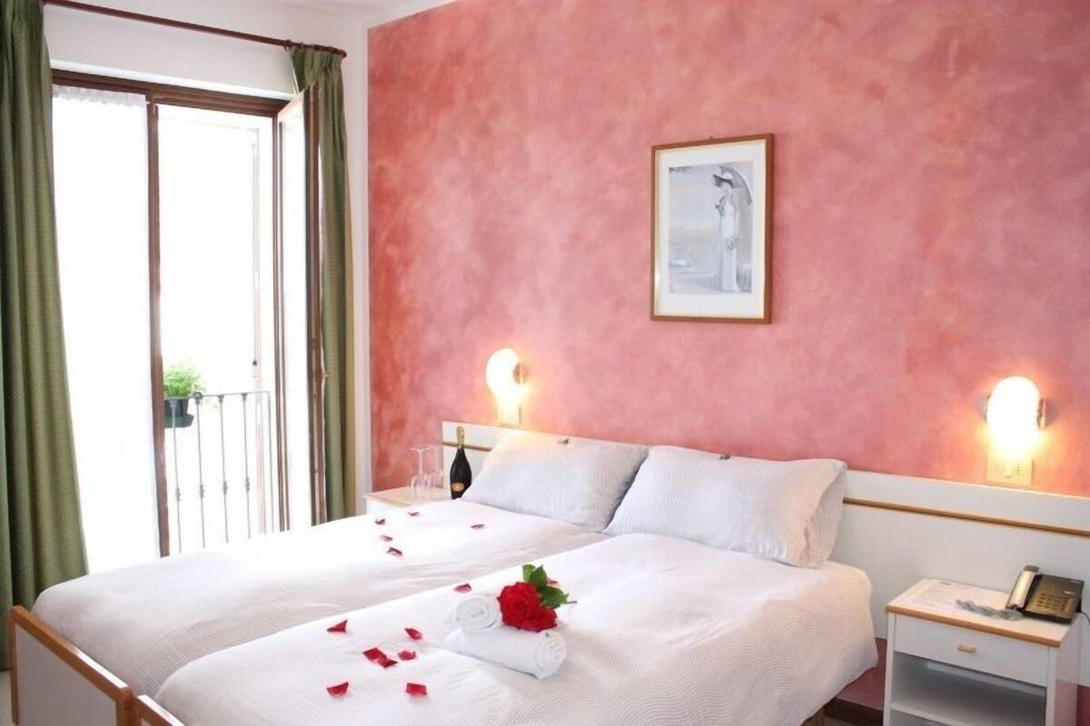 Ein Hotelzimmer mit zwei Betten, einem Balkon und einem Bild an der Wand.