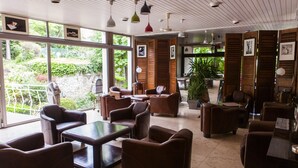 A spacious indoor area with leather sofas, a glass coffee table, and pendant lighting. - La Scala (Pithiviers)