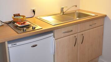 A compact kitchen with a microwave, sink, and a small refrigerator.