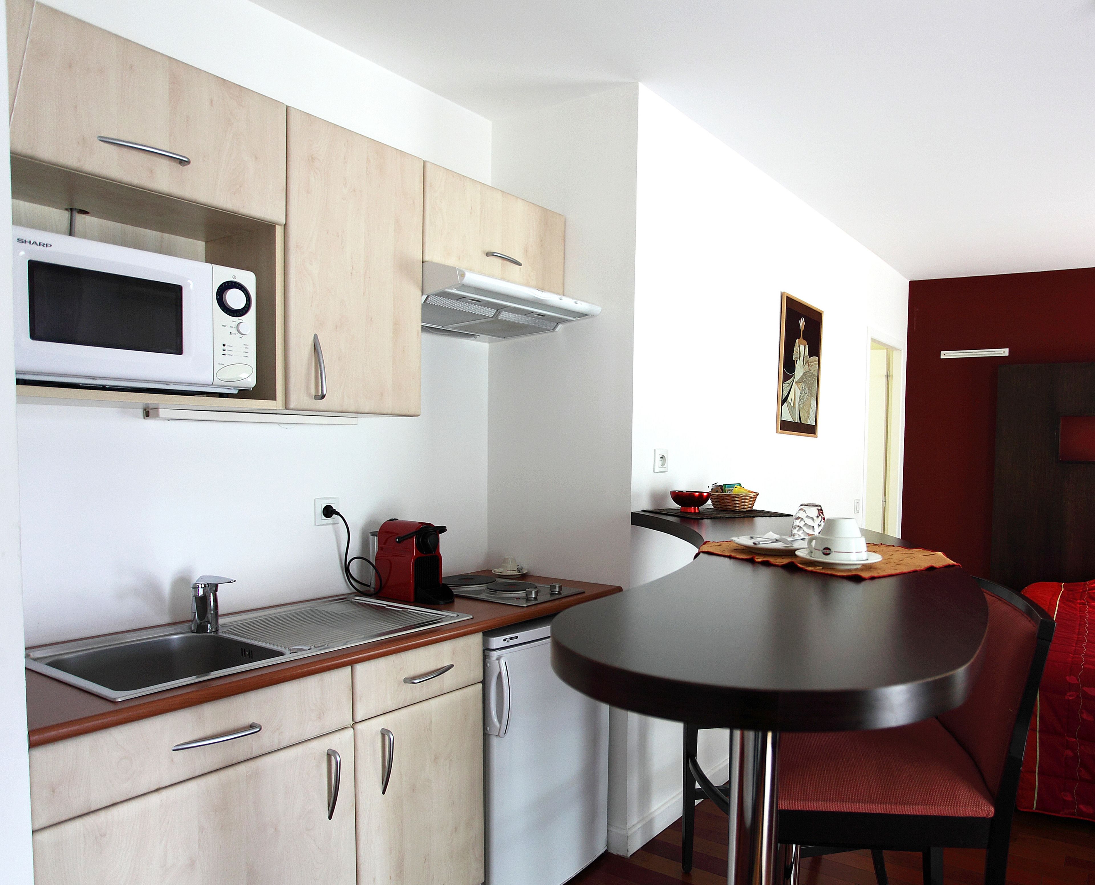 A compact kitchen with a microwave, sink, and a small dining area with a table and chair.