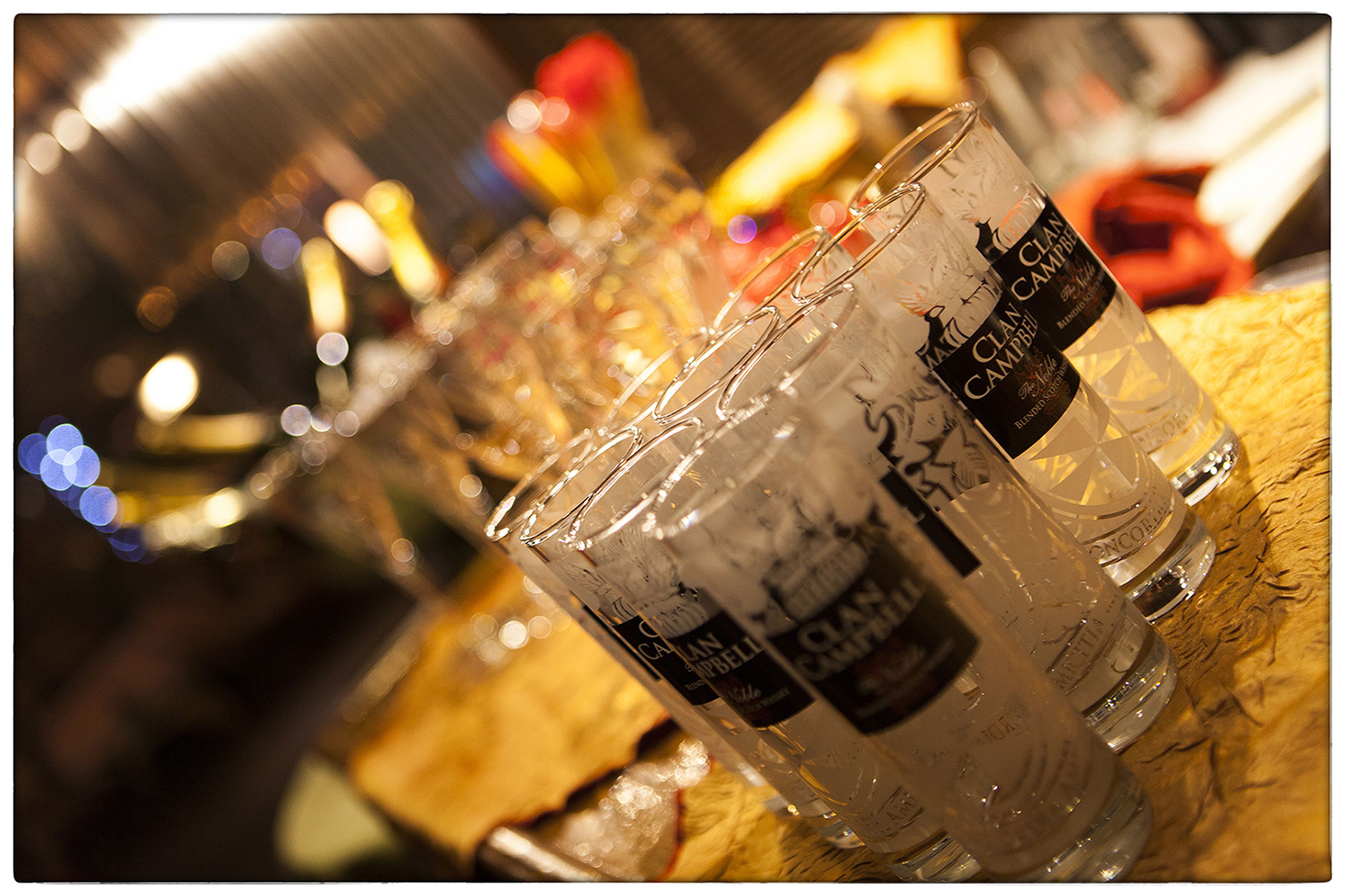 A row of glasses with "Clan Campbell" branding on a wooden surface.