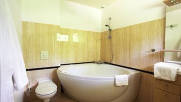 A bathroom with a bathtub, toilet, and a mirror.