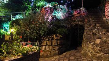 Un sendero de piedra que atraviesa un jardín con diversas plantas y una puerta decorativa.
