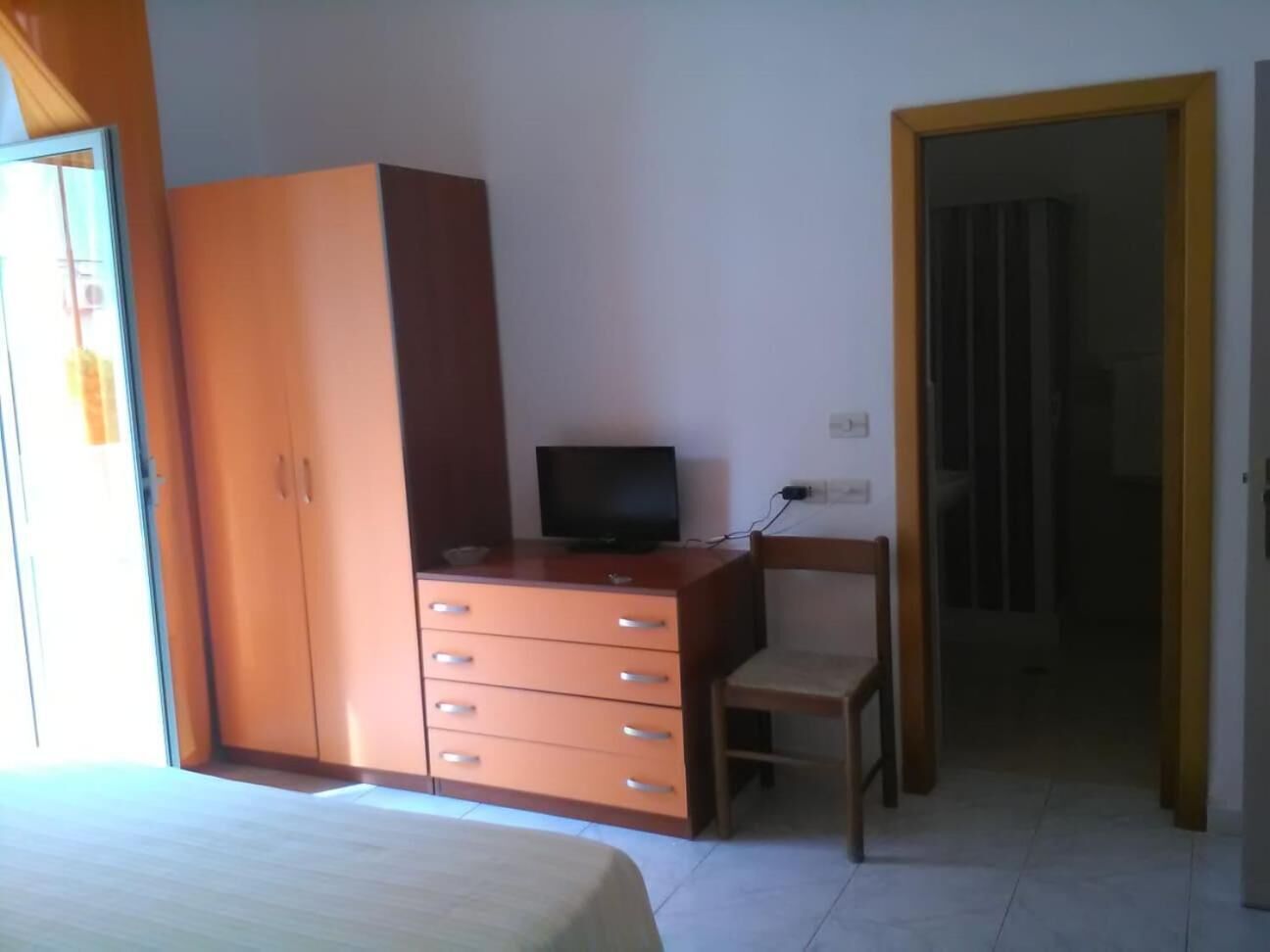 Una camera da letto con un letto, un armadio in legno, una scrivania con una sedia e una televisione.