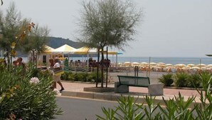 A beachside area with outdoor seating, umbrellas, and a bench. - Hotel Germania (Praia a Mare)