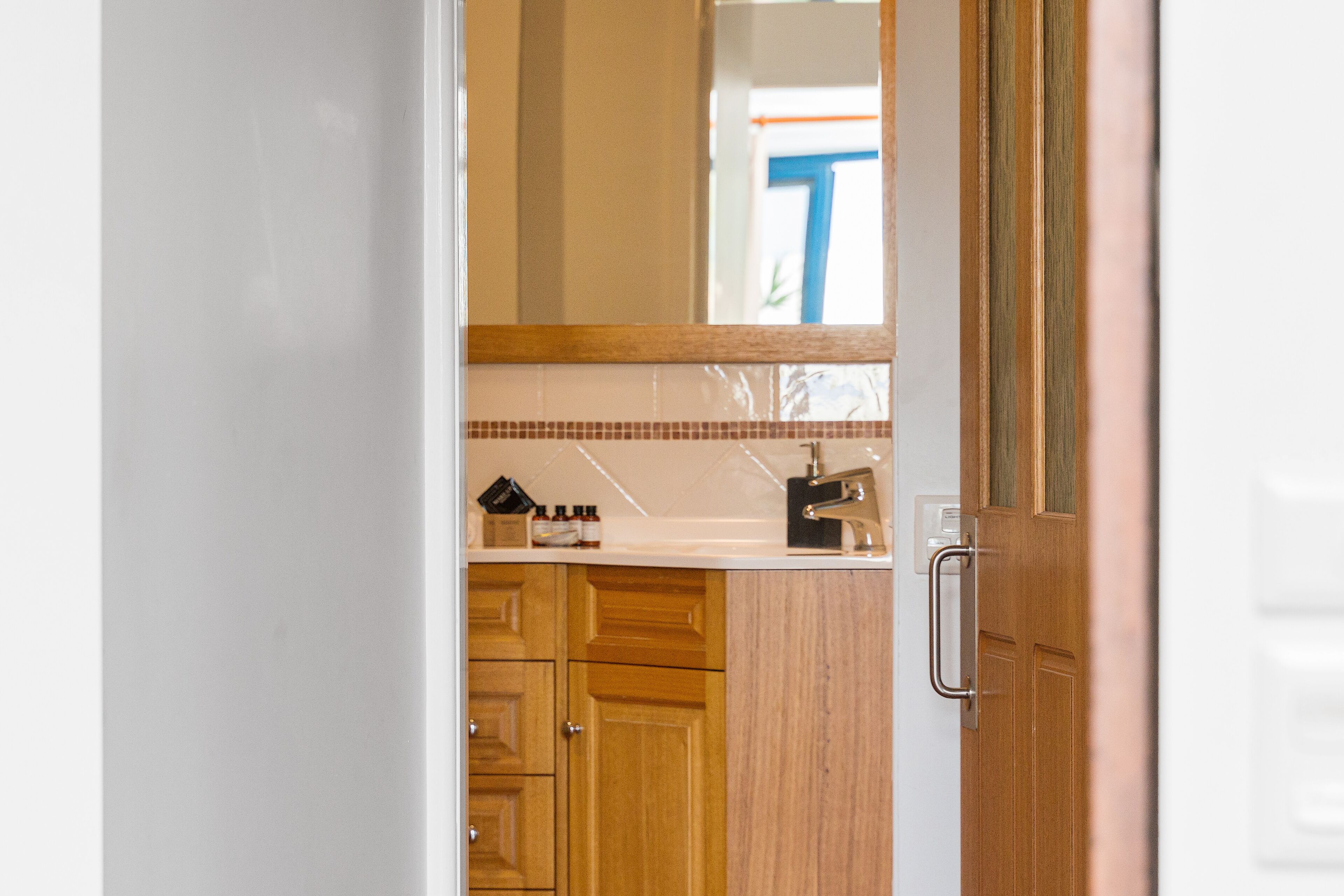 A bathroom with a wooden vanity, a mirror, and a towel rack.