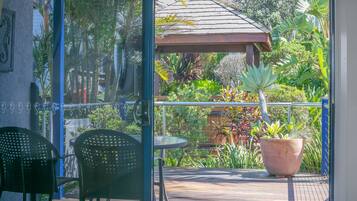 En terrasse med et bord og stole, omgivet af frodig vegetation og et pergola.
