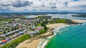 An aerial view of a coastal town with residential buildings, a beach, and a river.