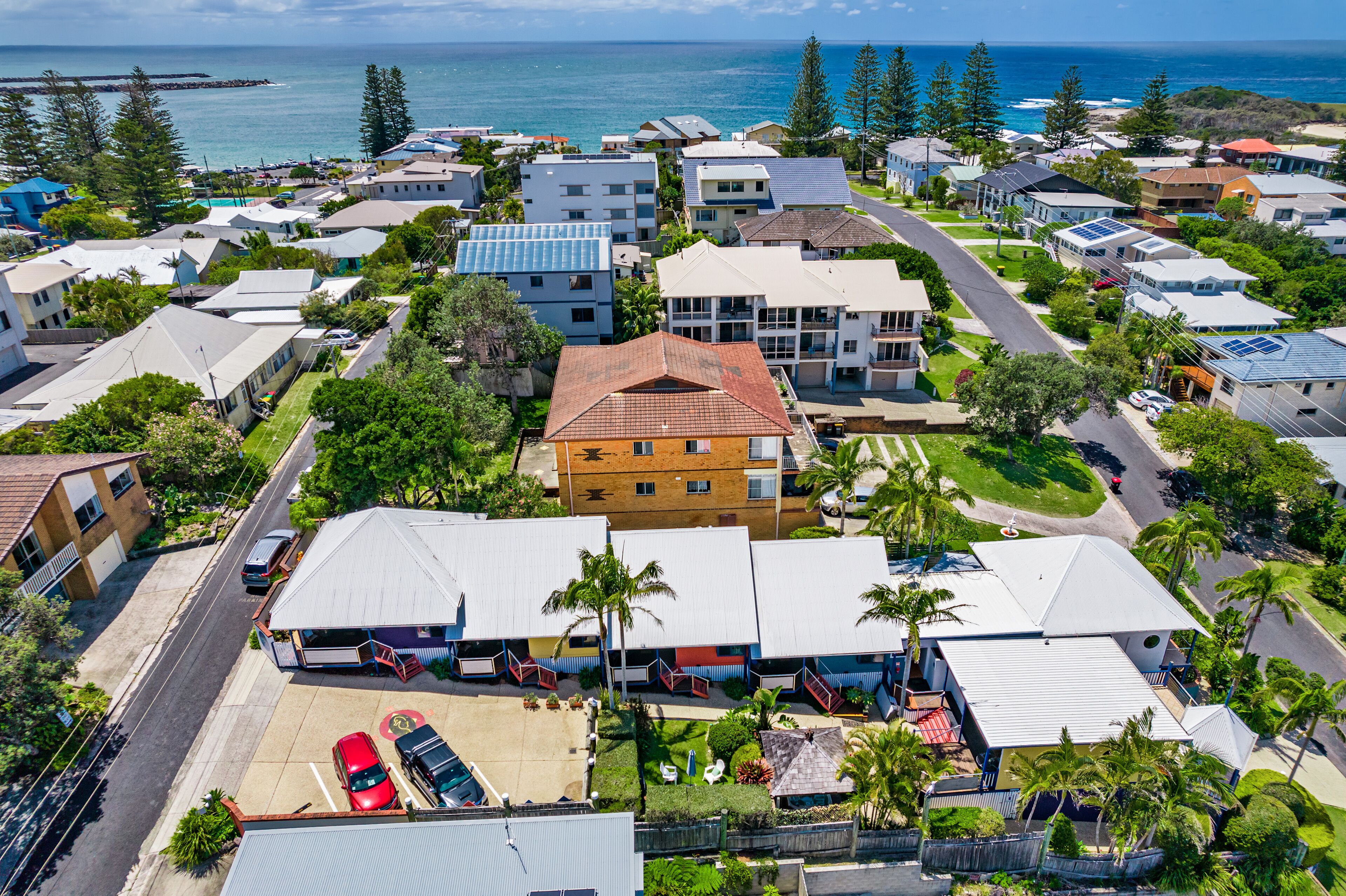 A residential area with houses, a parking lot, and a view of the ocean.