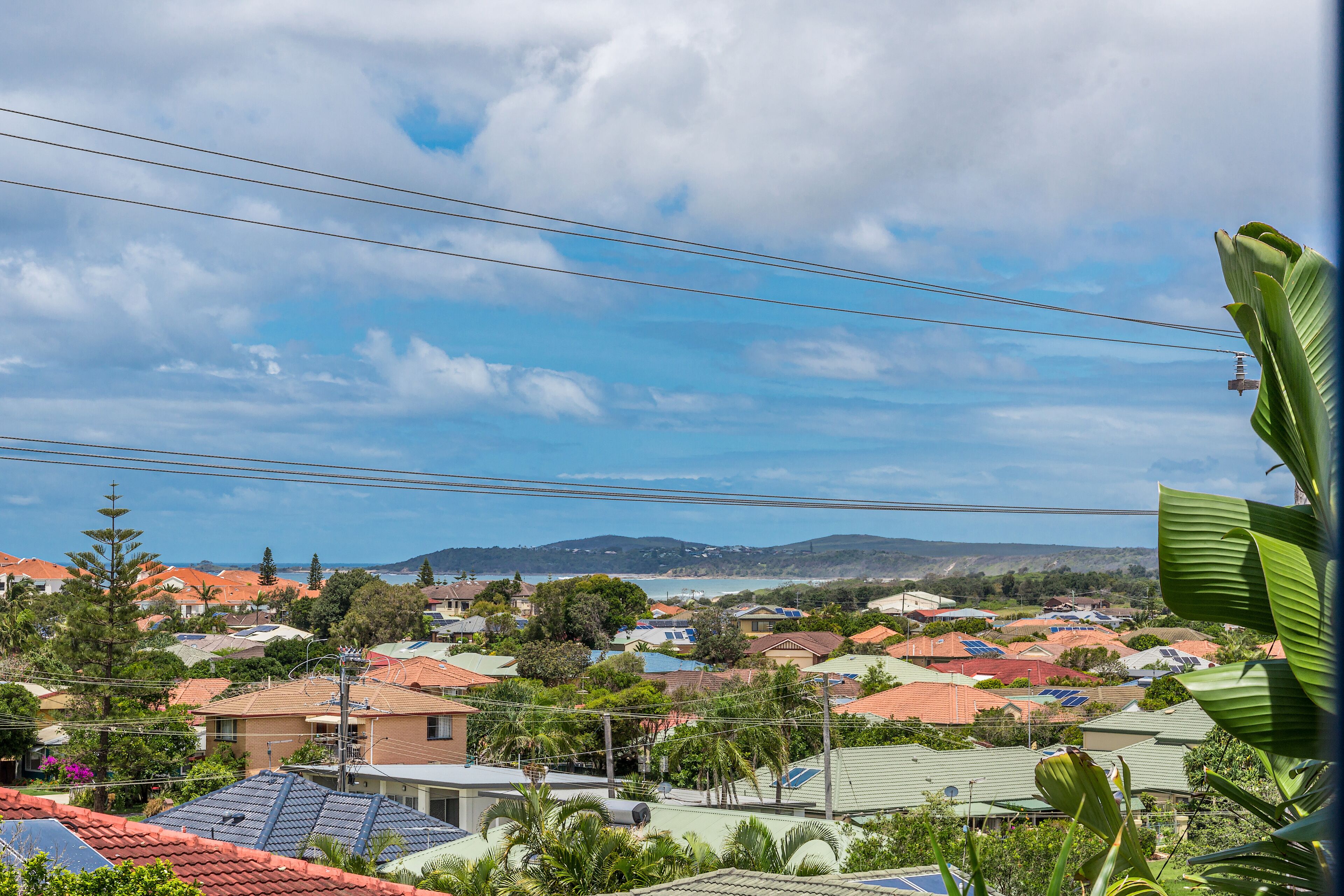 A residential area with houses, power lines, and a distant view of hills.